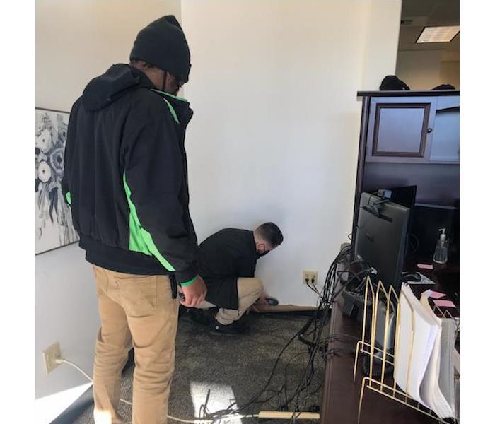 two servpro employees looking at carpet